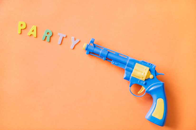blue and yellow plastic revolver toy with party sign